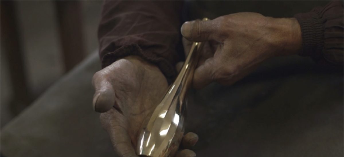 A caster's hands holding a polished cast vessel at Nousaku, Toyama